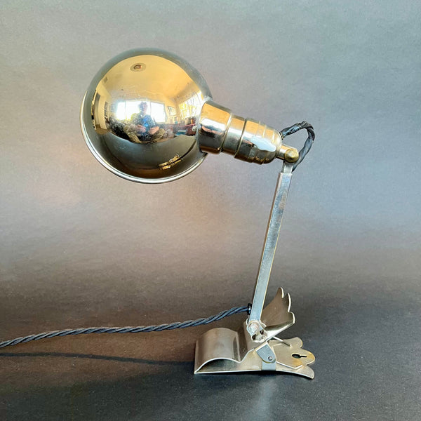Metallic clamp light with spherical head on a neutral background